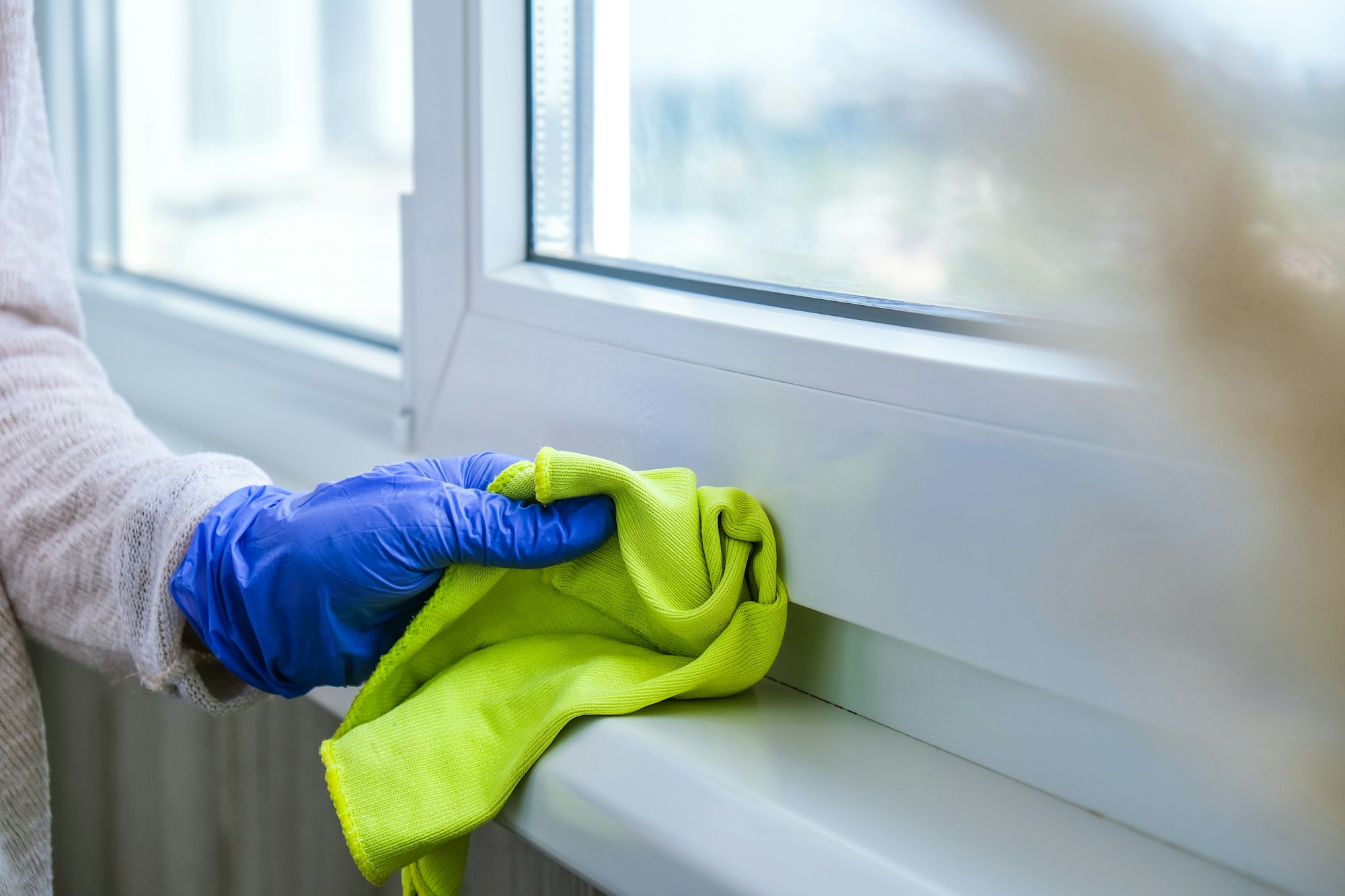 Cleaning the windowsill wiping dust by blue microfiber cloth for cleaning on the glass window rail B