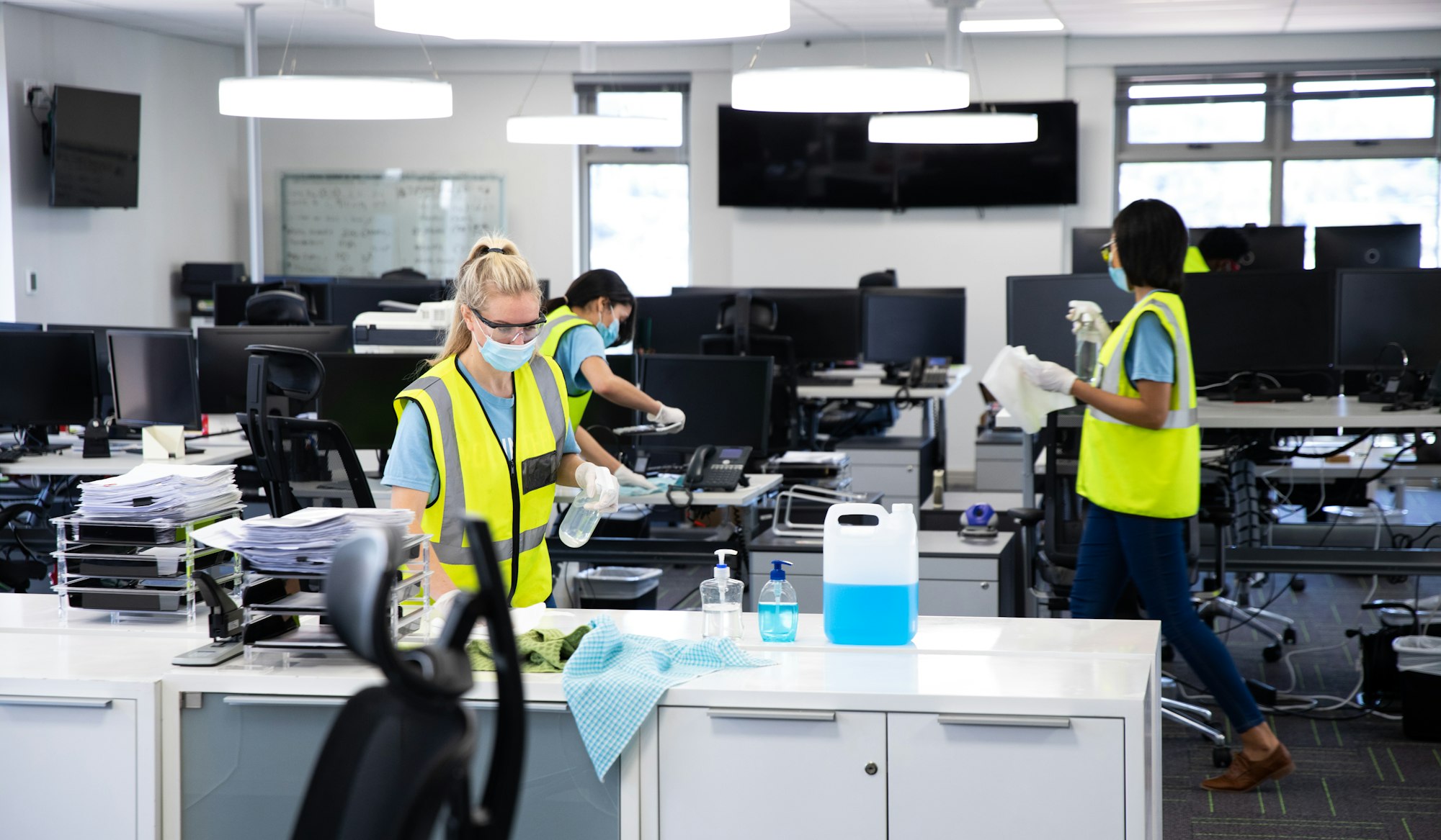 Team wearing hi vis vest and face mask cleaning the office using disinfectant